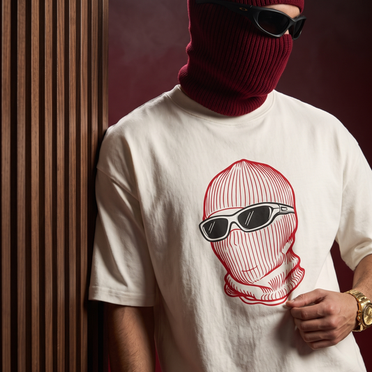 A person wearing an off-white graphic t-shirt with a red and black ski mask illustration, styled with a dark red balaclava, black sunglasses, and gold jewelry, leaning against a dark wood-paneled wall.
