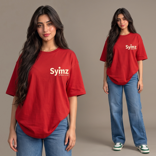 A model is shown in two poses wearing a red oversized t-shirt with 'Syzm' printed in white on the chest, paired with blue jeans, against a solid beige studio background.