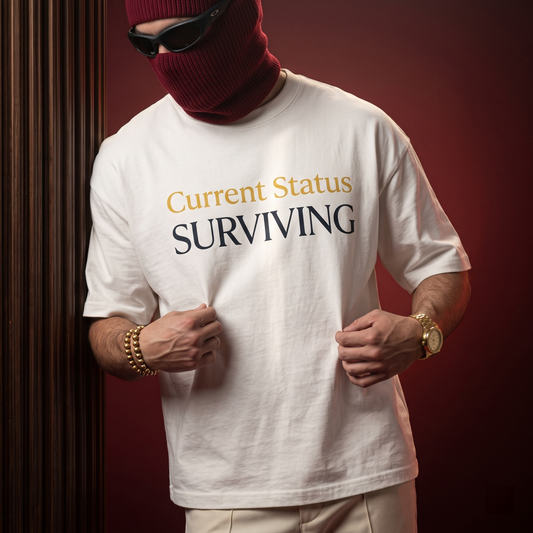 A person wearing a white graphic T-shirt with the words 'Current Status SURVIVING' in gold and dark navy lettering, styled with a burgundy knit balaclava, black sunglasses, gold bracelets, and a gold watch against a dark red and wood-paneled background.